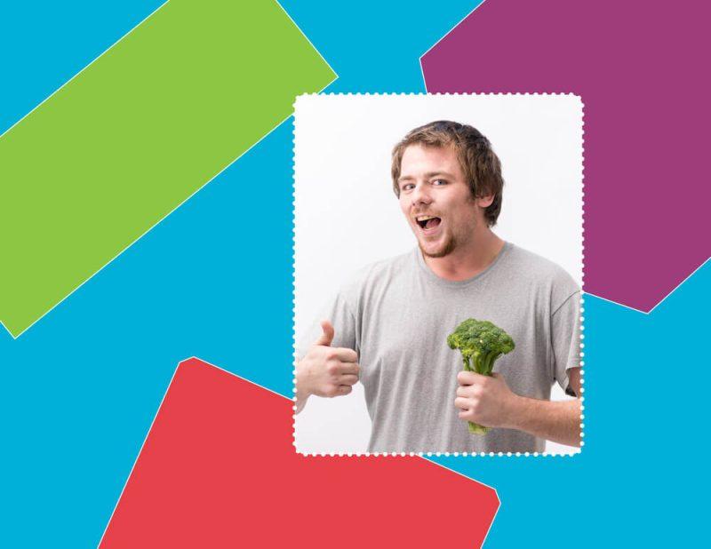 man with gray shirt posing for a meet our team photo, doing a thumbs up and holding broccoli in front of colourful background