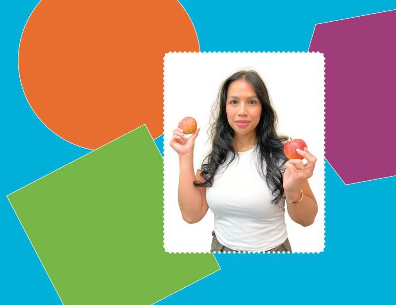 woman with white shirt posing for a meet our team photo, holding two apples in front of colourful background