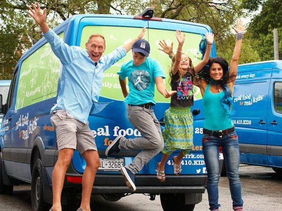 man, boy, girl and woman jumping happily in front of Real Food for Real Kids delivery van