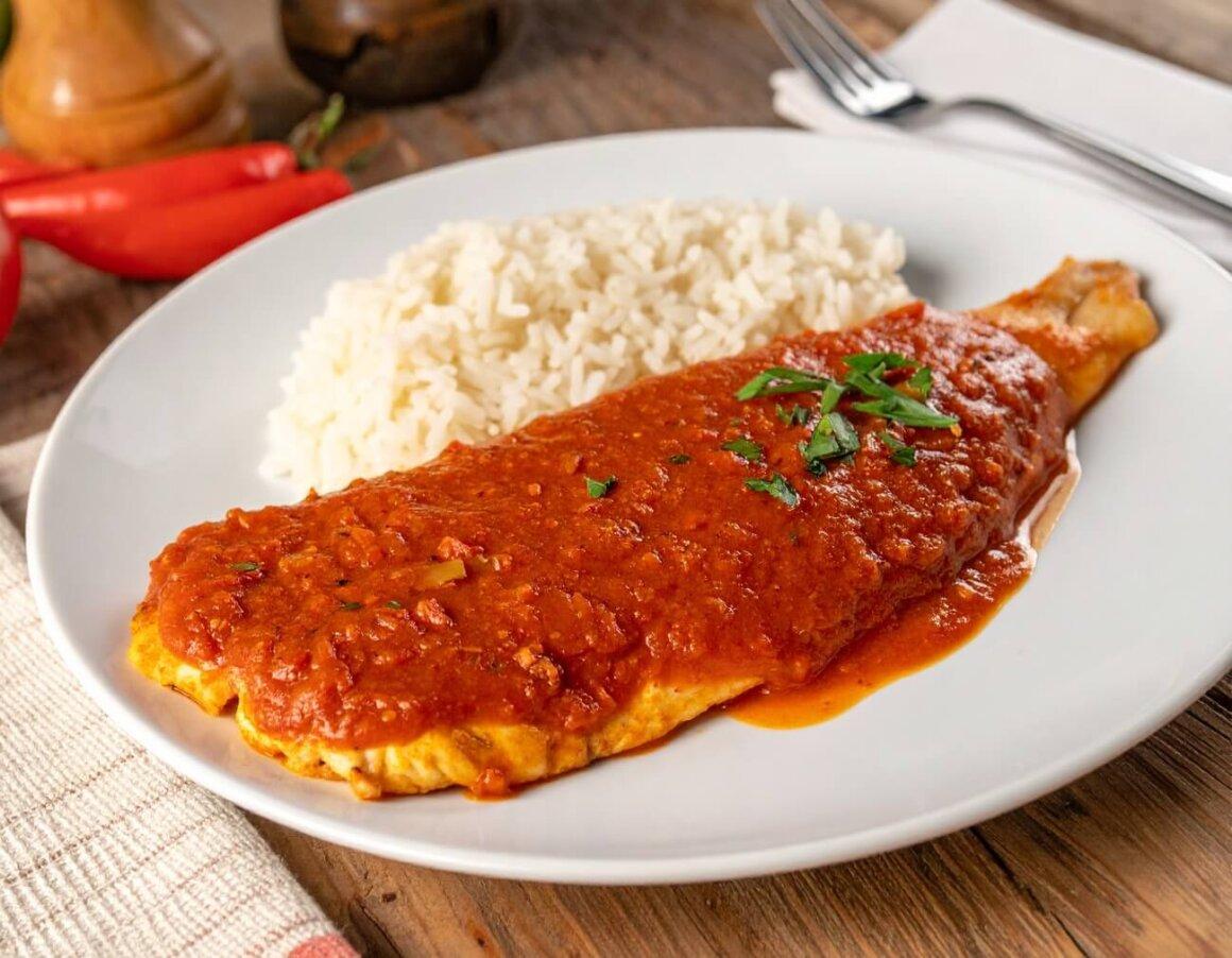 masala fish filet with masala marinade on top next to rice on a round white plate