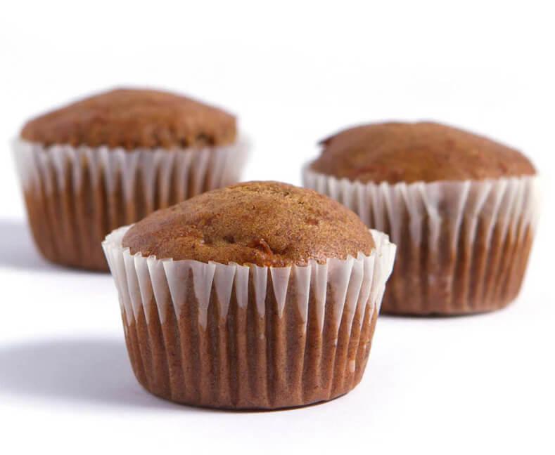 Three carrot muffins with white background, one more predominantly in the foreground