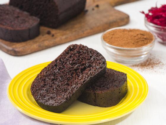 RFRK's cocoa beet loaf one slice on top of the other, served on a yellow plate next to cutting board with rest of the full loaf