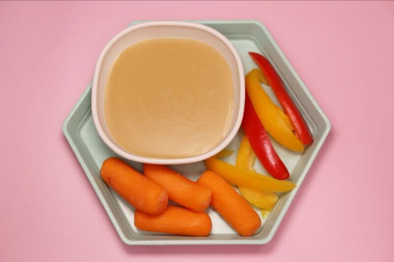 real food for real kids new golden miso dip alongside carrots, peppers for dipping and pink background