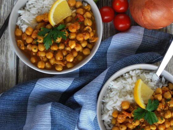 two bowls of rfrk chickpea chowder topped with cilantro and lemon wedge served over rice