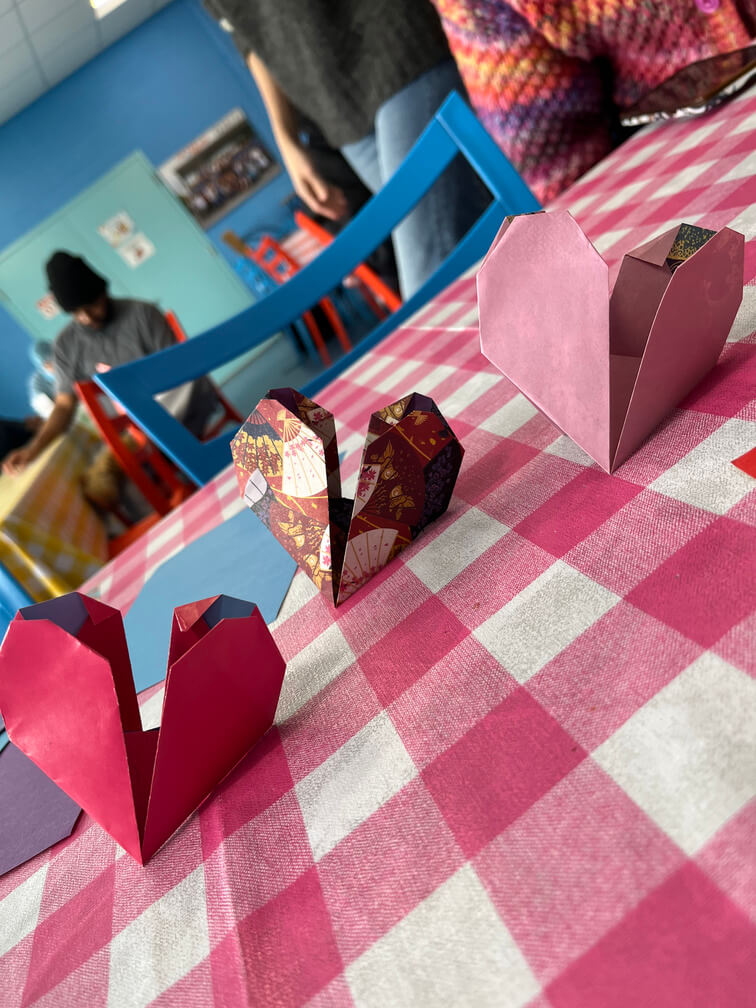 close up of three origami shaped as hearts on top of checkered tablecloth