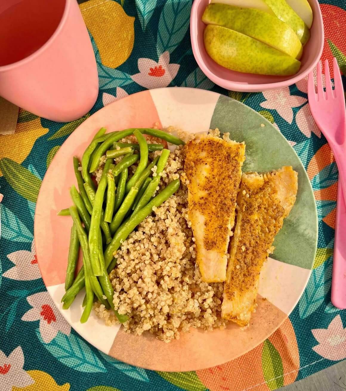 carrot and flax fish on colourful plate served with quinoa and green beans and pear next to pink cup