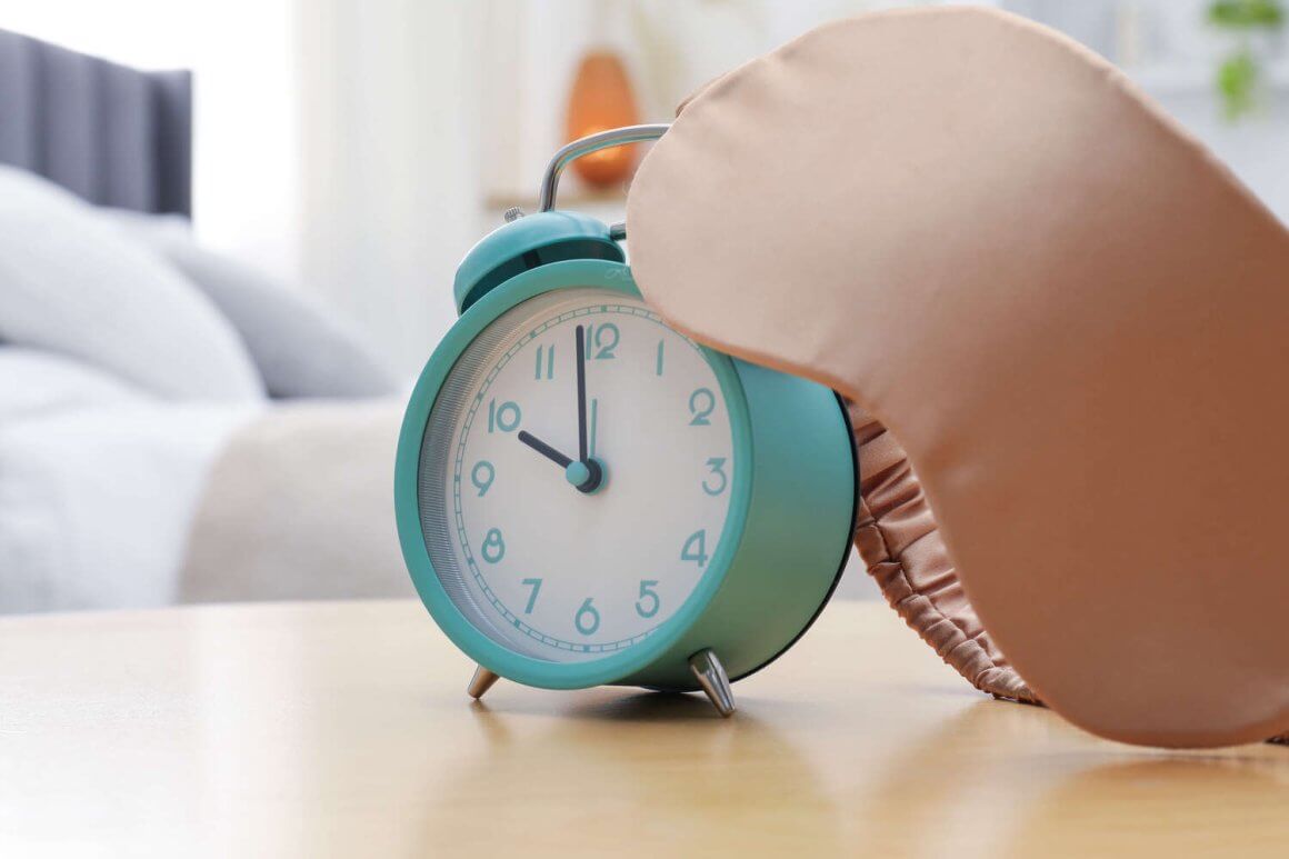 close up of blue clock next to sleeping mask