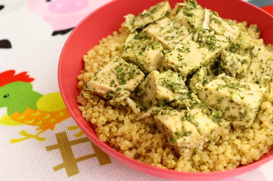 rfrk's chicken pesto and quinoa served to kids with tomato allergy in a red bowl next to a placemat with cartoonish bird designs