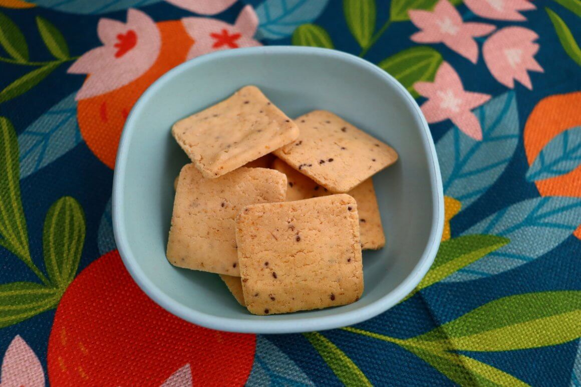 himalayan salt crackers served as a gluten-free option inside tiny blue bowl on top of placemat with pink flowers and colourful leaf designs