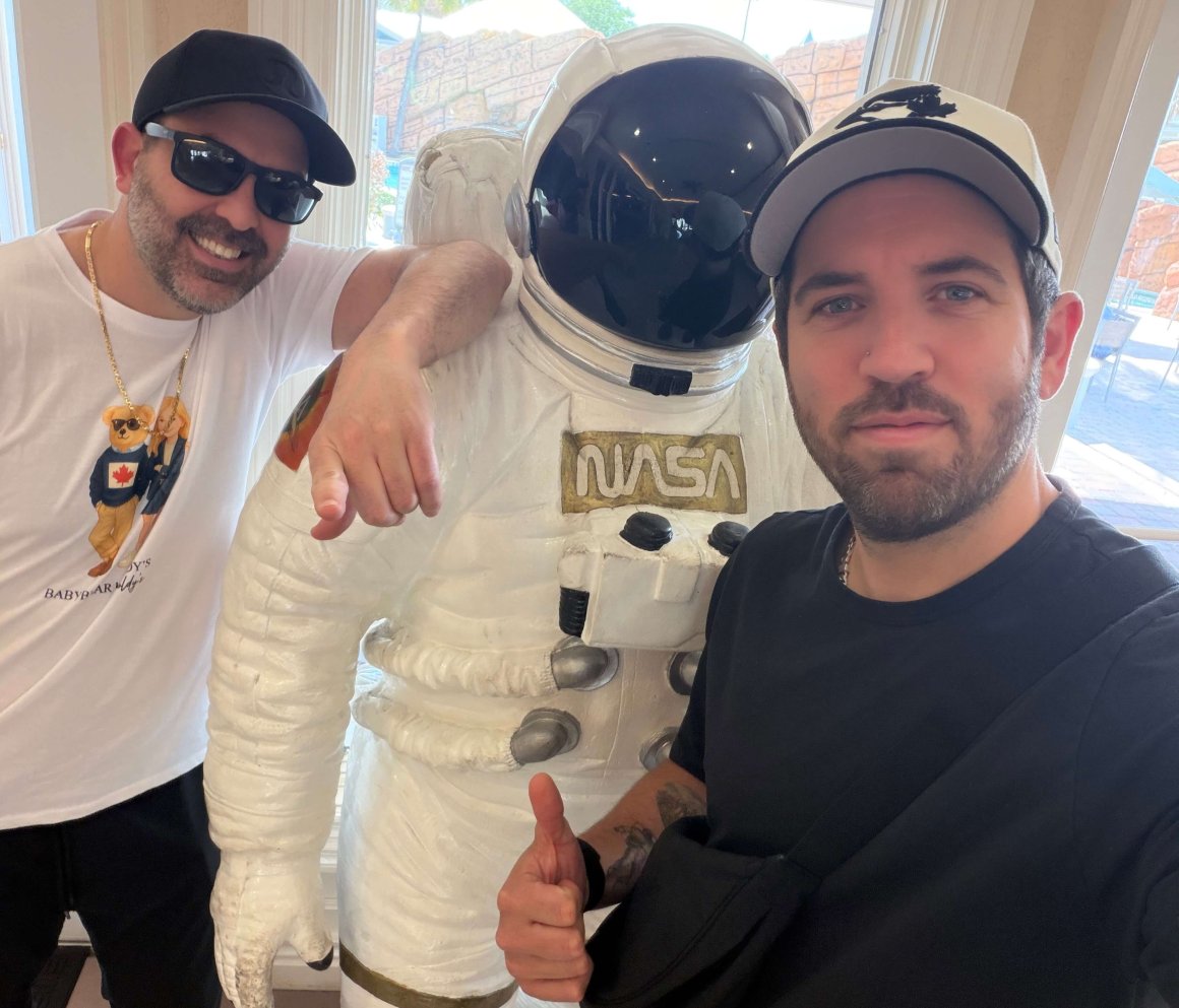new: cinnamon & chia oatmeal! 2 two men posing with thumbs up wit astronaut outfit in between them