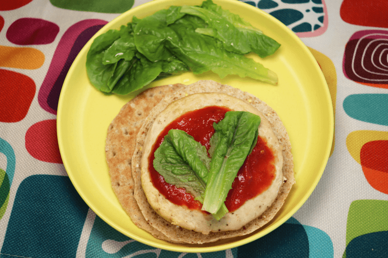 chicken burger on plate with homemade Real Food Ketchup, romaine lettuce pieces and multigrain pita bun