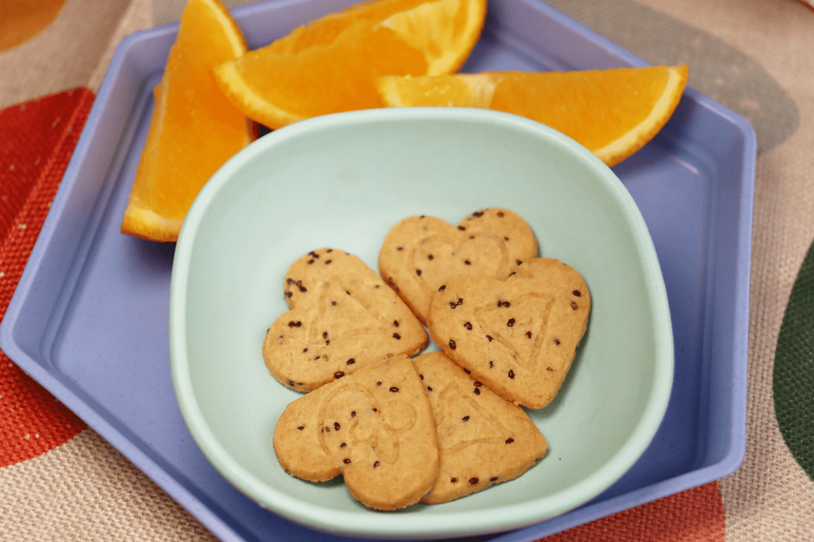 local food week 2026! 6 five heart shaped coconut & chia cookies in small light blue bowl next to orange slices in the background