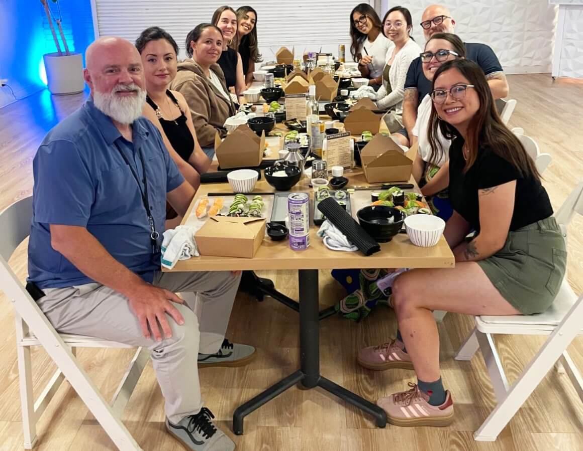 rfrk team building group shot with ten people smiling and sitting around a table participating in a sushi making class