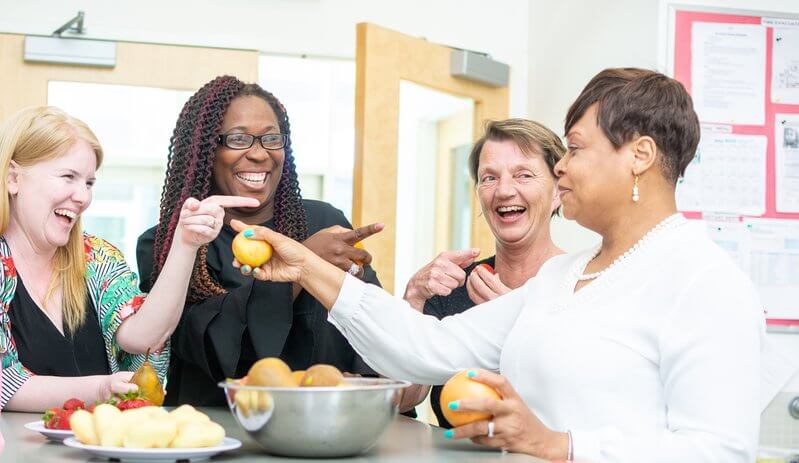 a group of ECE women gathered around a table smiling and bonding