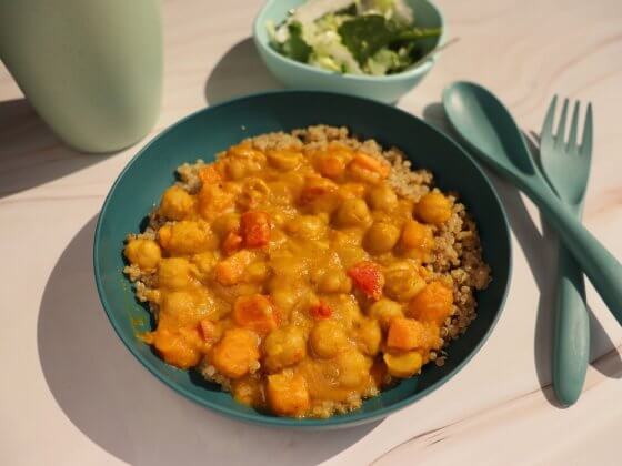 bowl of vegetarian dish pumpkin chana curry in a teal bowl next to teal kids cutlery